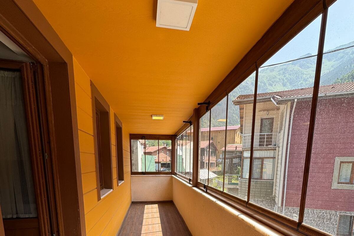 A corridor with wooden flooring, large windows, and a view of buildings outside.