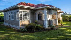 A two-story house with a red-tiled roof, a front porch with columns, and a well-maintained lawn. - Gatundu Peaceful Tea Farm Stay w/activities (Gatundu)