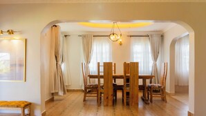 A dining area with a wooden table and chairs, a bench, and a chandelier. - Gatundu Peaceful Tea Farm Stay w/activities (Gatundu)