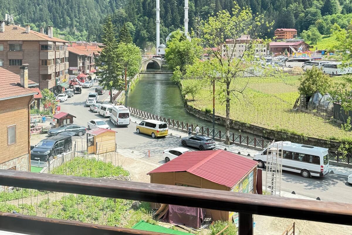 A view of a town with a river, a mosque with two minarets, and a bridge in the background.