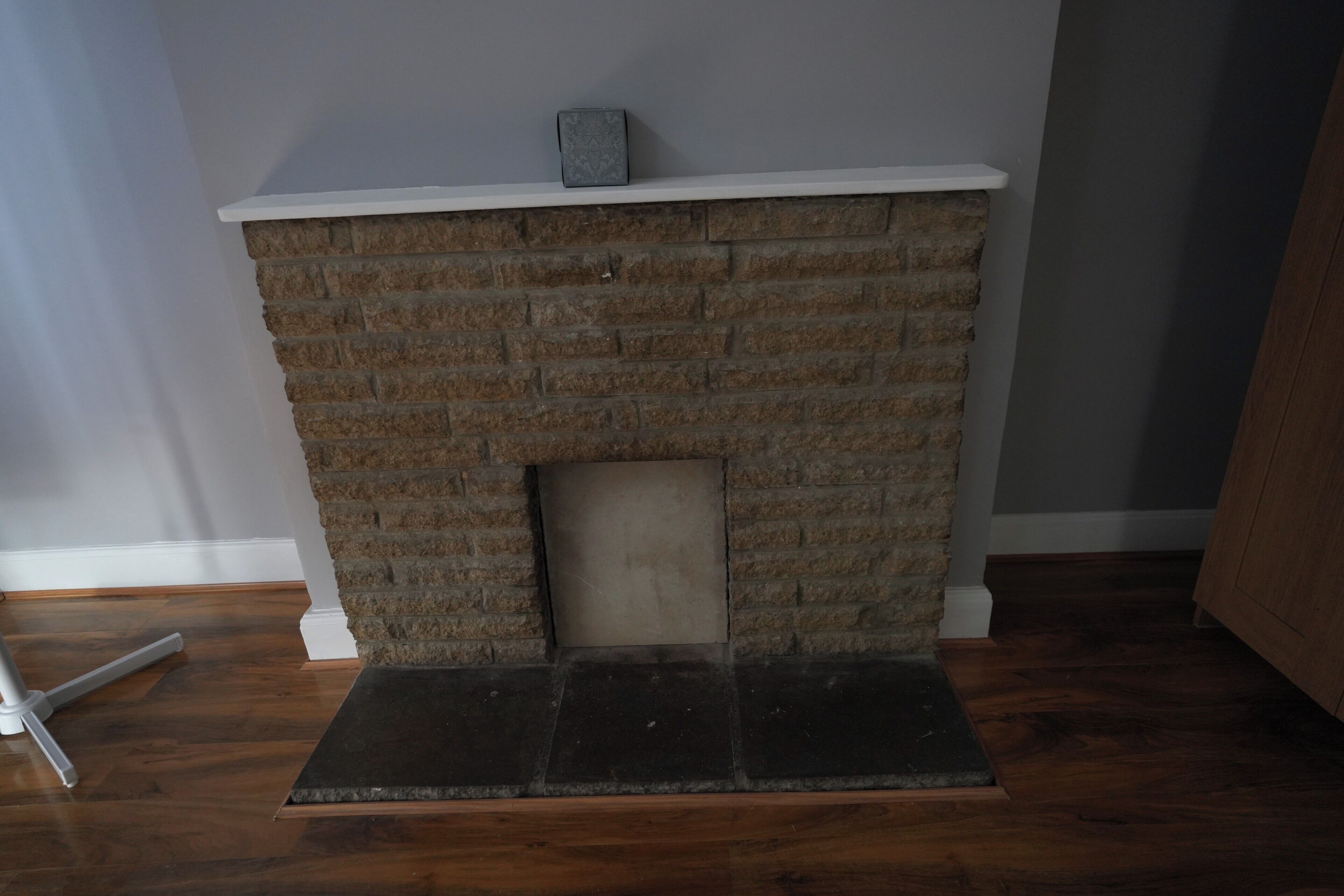 A brick fireplace with a white mantel and a small book on top.