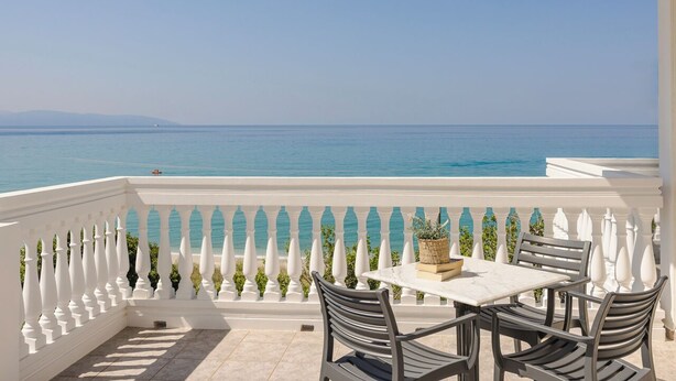 A balcony with a white balustrade, a table with chairs, and a view of the sea. - Charming 1-bedroom Penthouse apartment in Lourdata (Lourdata)
