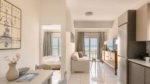 A modern hotel room with a dining area, kitchenette, and a balcony with a view of the sea. - Charming 1-bedroom Penthouse apartment in Lourdata (Lourdata)