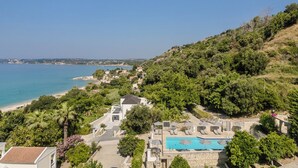 A coastal property with a swimming pool, lounge chairs, and a view of the sea. - Charming 1-bedroom Penthouse apartment in Lourdata (Lourdata)
