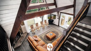 Un espace de vie de style loft avec un escalier en bois, un canapé en cuir, une table basse et un téléviseur fixé au mur.