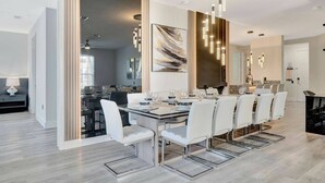 Un comedor moderno con una mesa larga, sillas blancas y lámparas contemporáneas.