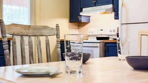 Una cocina con una silla de madera, un vaso de agua, un plato y un bol sobre la encimera.