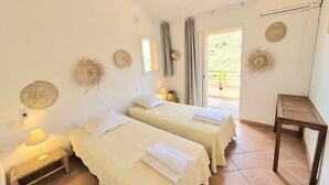 Ein Zimmer mit zwei Betten, einem kleinen Tisch und einem Balkon mit Blick.