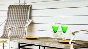Una mesa con dos vasos de líquido verde, un plato y una silla con funda de cuadros.