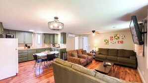 Un espacio habitable compacto con comedor, sofá y televisor montado en la pared.