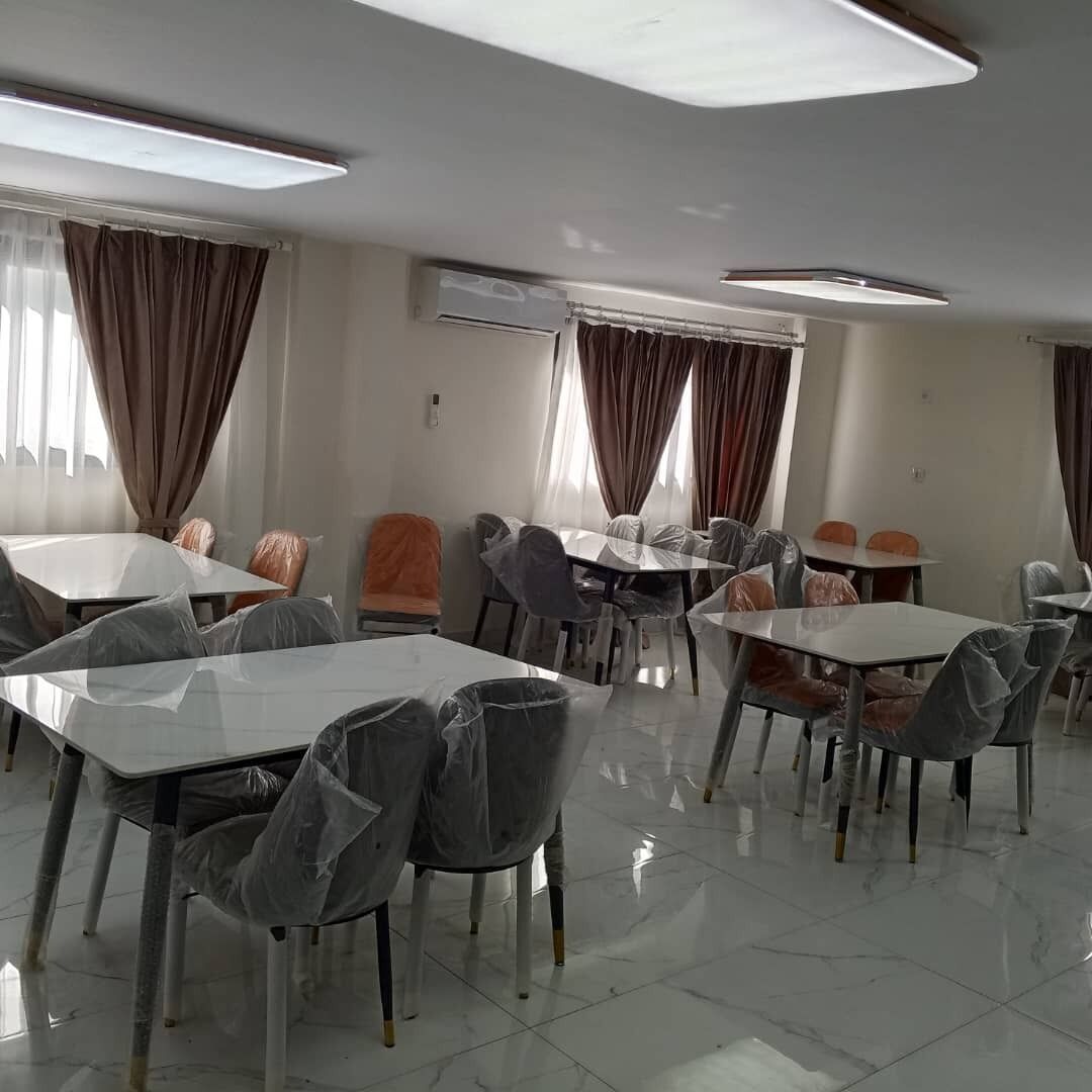 Un comedor de hotel con mesas y sillas, unidades de aire acondicionado y cortinas.