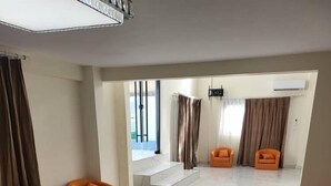 A spacious room with a marble floor, orange armchairs, a small round table, and a staircase leading to another area. - Melia's Hôtel Diamniadio  (Diamniadio)