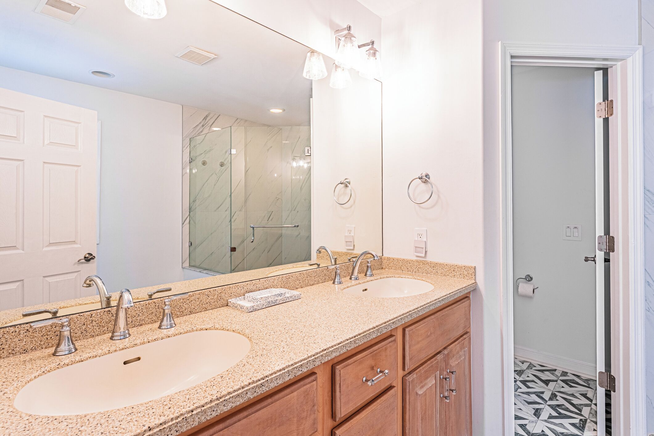A bathroom with two sinks, a large mirror, and a shower area.