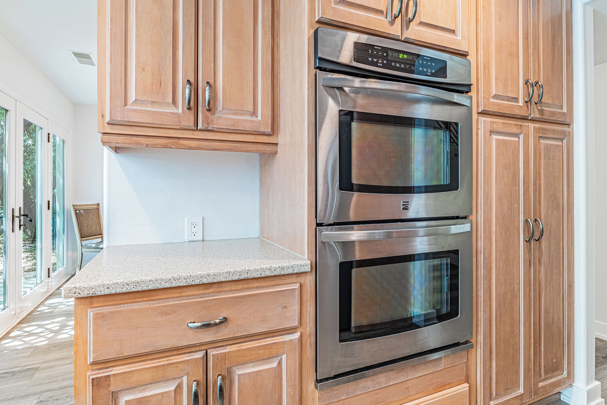 A kitchen with wooden cabinets, a double oven, and a granite countertop.