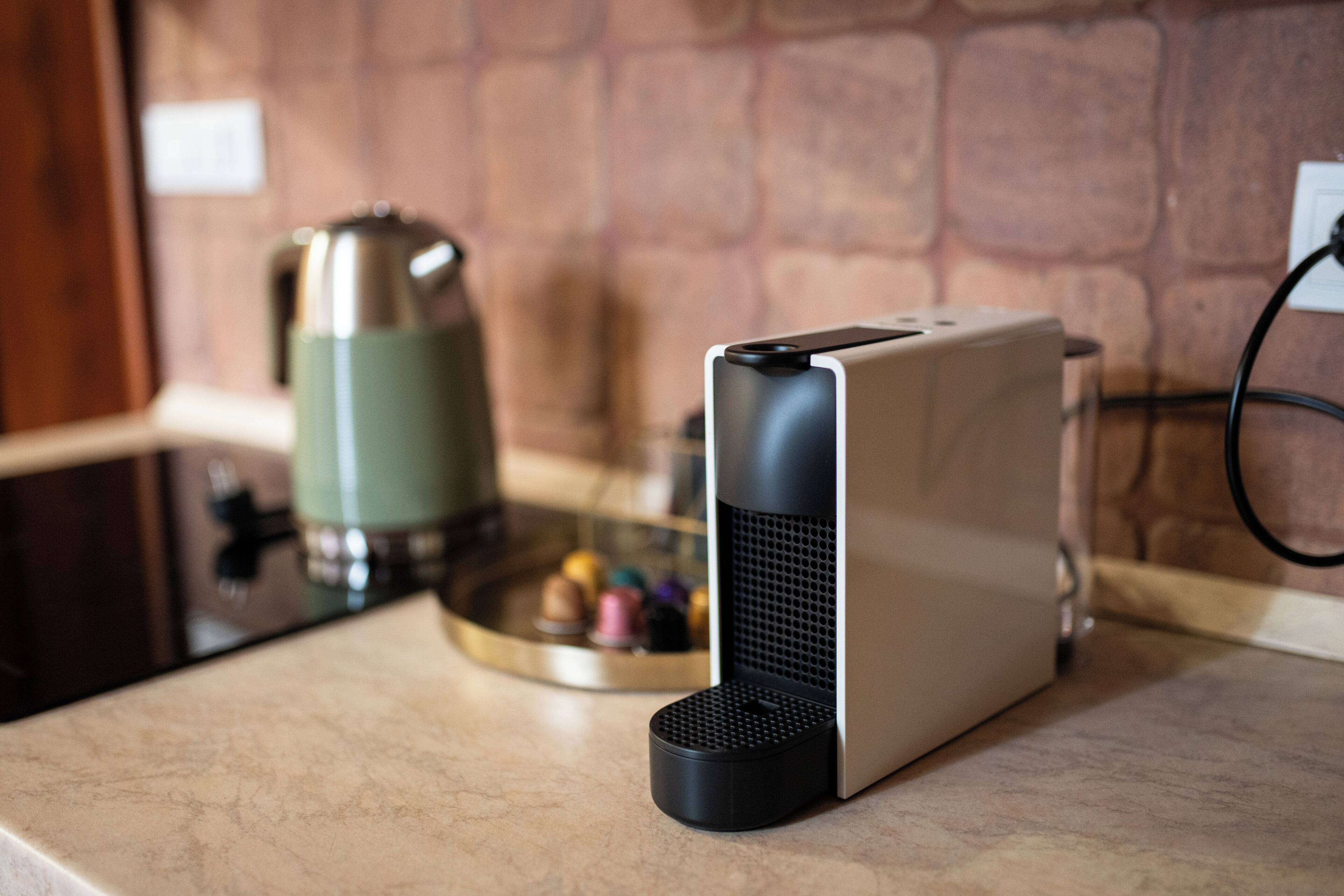 A kitchen with a coffee maker, a kettle, and a modern coffee machine on the counter.
