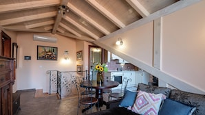 A dining area with a wooden table, chairs, and a vase of flowers. - Antaeus Old Town Residence (Dubrovnik)