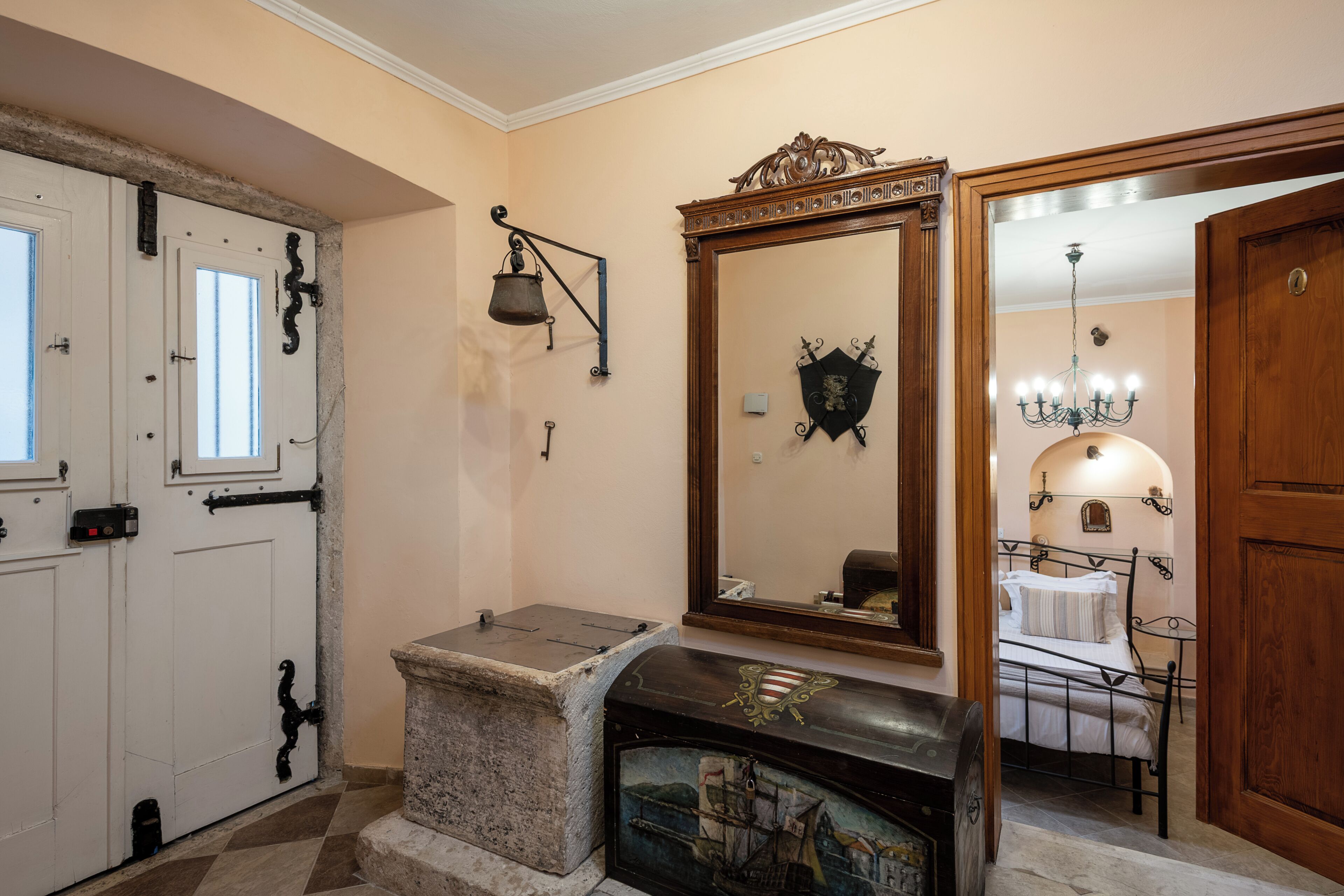 Une pièce comprenant un lit, une cheminée en pierre, un miroir et une porte avec une fenêtre.