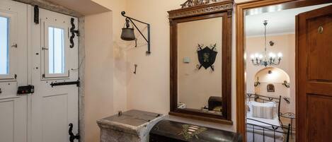 A room with a bed, a stone fireplace, a mirror, and a door with a window.