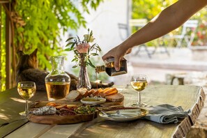 A table set with a bottle of olive oil, two glasses of wine, bread, cheese, and olives. - Luxury Vacation Rental | Idyllic Countryside Escape in Provence (Châteauneuf-Grasse)