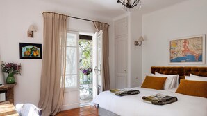A bedroom with a bed, a desk, a chair, a vase with flowers, and a map on the wall.
