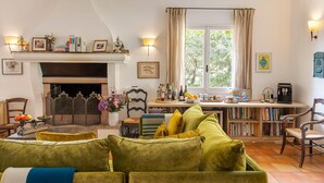 A cozy living room with a fireplace, a coffee table, and a bookshelf.