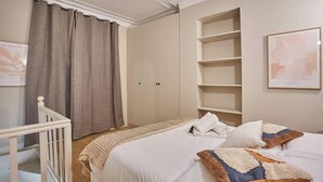 Una habitación de hotel con cama, armario, estantería y una escalera.