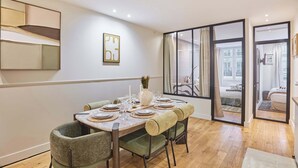 Un comedor con una mesa redonda dispuesta para cuatro personas, rodeada de sillas tapizadas.