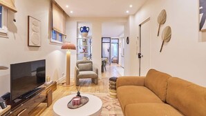 Una sala de estar moderna con una televisión de pantalla plana, una mesa de centro redonda, un sofá y una estantería.