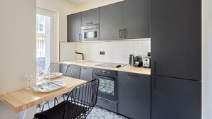 A modern kitchen with dark cabinets, a microwave, an oven, and a sink. - Elegant and modern apartment  Eiffel Tower (Paris)