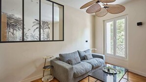 A modern living room with a grey sofa, a glass coffee table, and a large framed artwork on the wall. - Elegant and modern apartment  Eiffel Tower (Paris)