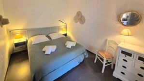 Una habitación de hotel con una cama, lámparas de noche, un escritorio con una silla y un aparador.