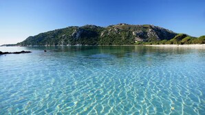 A clear coastal view with a mountain in the background.