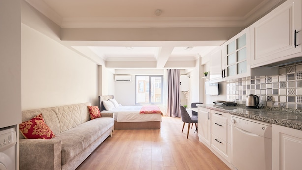 Ein modernes, helles Zimmer mit Bett, Sofa, Essbereich und Küche.