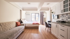 Ein modernes, helles Schlafzimmer mit Bett, einer Couch und einem Schreibtisch.