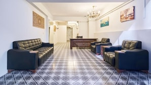 Ein geräumiger Wohnbereich mit Schachbrettmuster-Boden, Ledersofas, einem Holztisch und einer Chandelüstere.