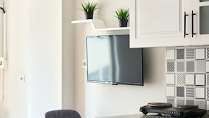 Eine moderne Küche mit weißen Schränken, einer Granitarbeitsplatte und einem integrierten Fernseher.