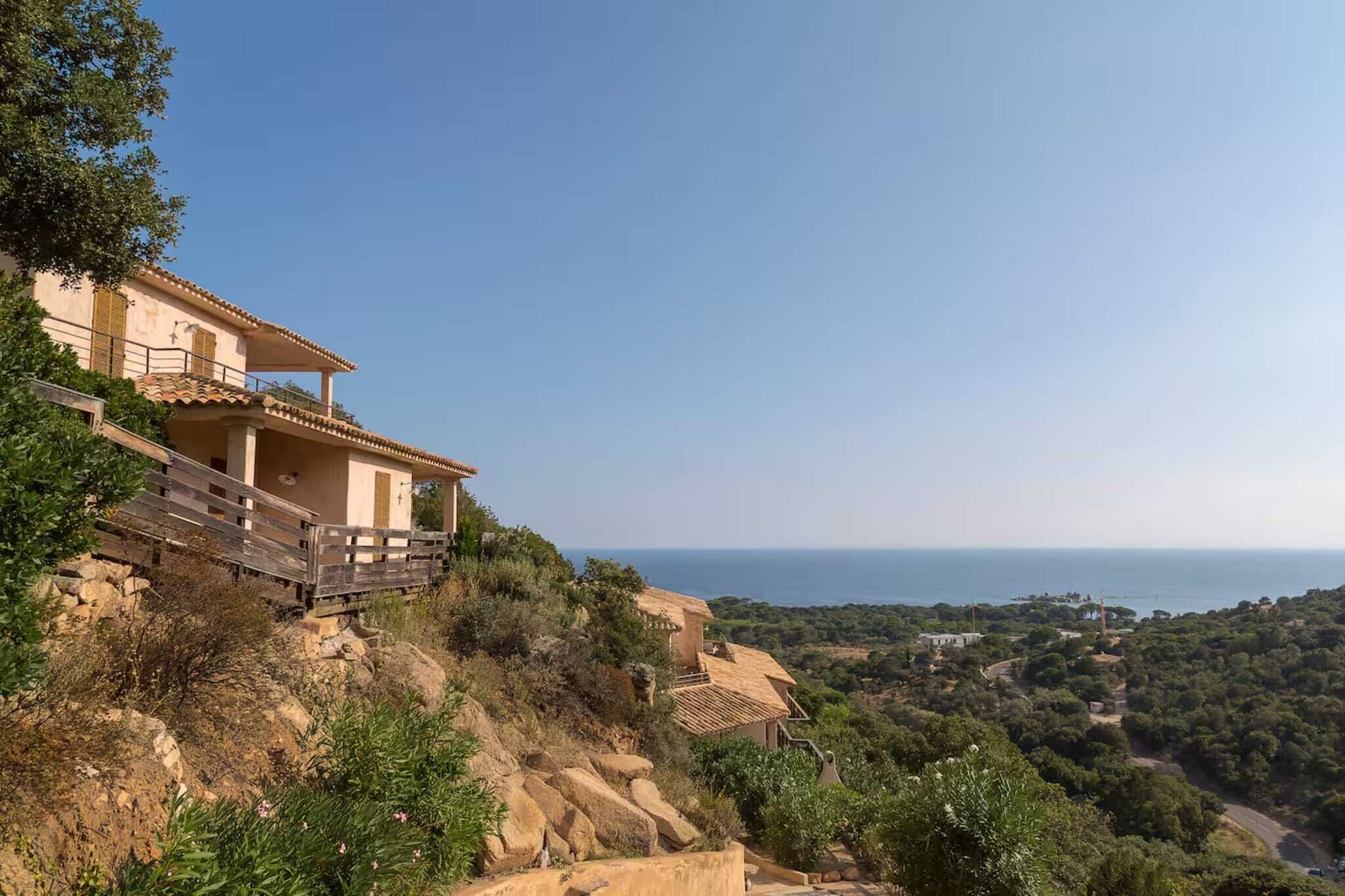 Una villa en una ladera con balcón que domina un paisaje costero.