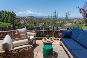 An outdoor seating area with wicker furniture, a blue sofa, and a small table with cups and a plant.