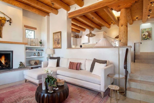 A living room with a fireplace, a sofa, a coffee table, and a staircase.