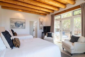 A room with a large bed, two smaller beds, a TV, and a sofa.