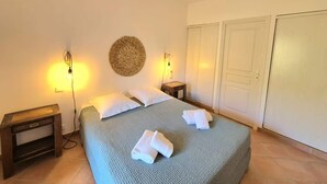 A bedroom with a bed, two bedside tables, a wall-mounted lamp, and a wardrobe.