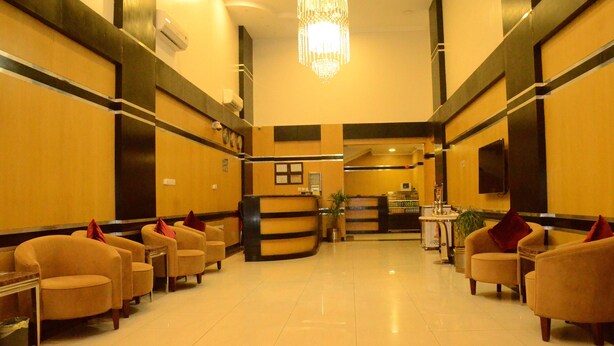 A hotel lobby with a reception desk, several armchairs, a chandelier, and a clean, tiled floor. - MASSET ALMASEM5 SERVICED APARTMENTS (Al-Hofuf)