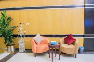 A reception area with two armchairs, a small table, a potted plant, and a decorative piece.