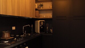 Een kleine keuken met een kookplaat, magnetron en een spoelbak.