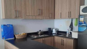 A kitchen with wooden cabinets, a black countertop, a stove, a sink, and a refrigerator.