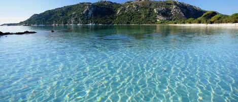 Una vista despejada de una playa con aguas tranquilas y una montaña al fondo.