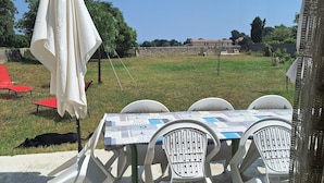 Une table entourée de quatre chaises en plastique blanc, recouverte d’une nappe, le tout posé sur une surface en béton.