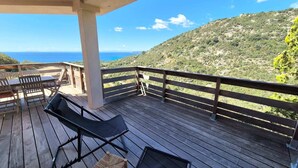 A wooden deck with a view of the sea and hills.