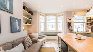 A cozy kitchen with a wooden countertop, a built-in bench, and a view through large windows. - Stunning 2-bedroom Flat in Fulham (London)