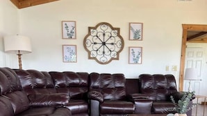 Un soggiorno con un divano modulare in pelle marrone scuro, un tappeto decorato e un tavolino in legno.